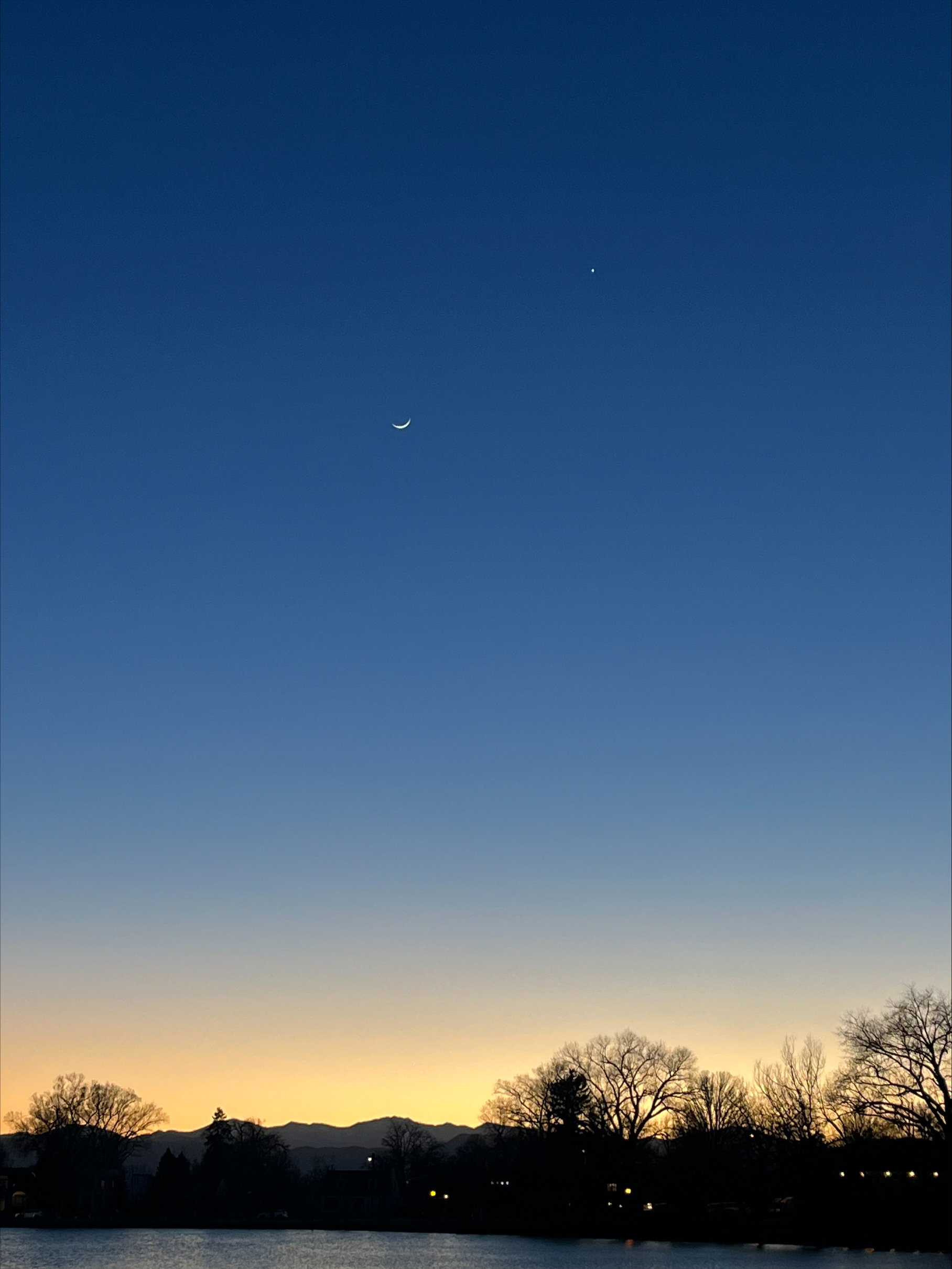 The calm Deep Blue-Black evening sky over a silhouette of the city in the distance